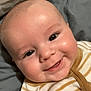 baby, smiling, face, infant, portrait, onesie, striped_clothing, cheeks, lying_down, bed, pillow, happy, cute, skin, head, eyes, mouth, person, child, indoors