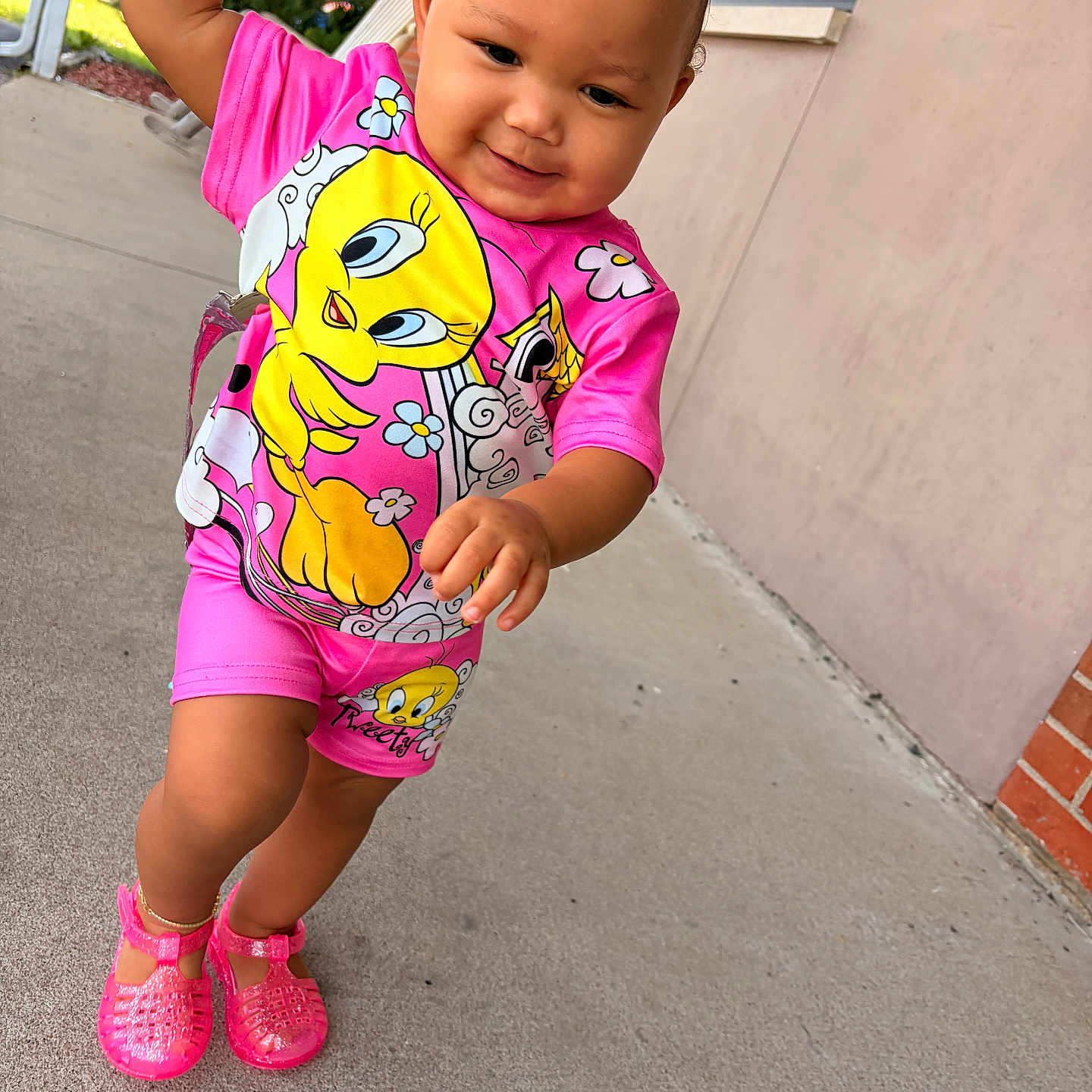 Lauryn joined the competition — help win amazing prizes! toddler, child, pink_clothing, tweety_bird, smiling, outdoor, sidewalk, shoes, yellow_hair_clip, cute, happy, person, shorts, cartoon_character, walking, concrete, building, wall, daylight, playful