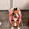 Lauryn is registered to the contest to win money with this photo: toddler, baby, child, bottle, pacifier, pink, bow, sitting, shoes, sneakers, floor, wall, chair, baby_chair, clothing, indoor, cute, person, drink, accessory