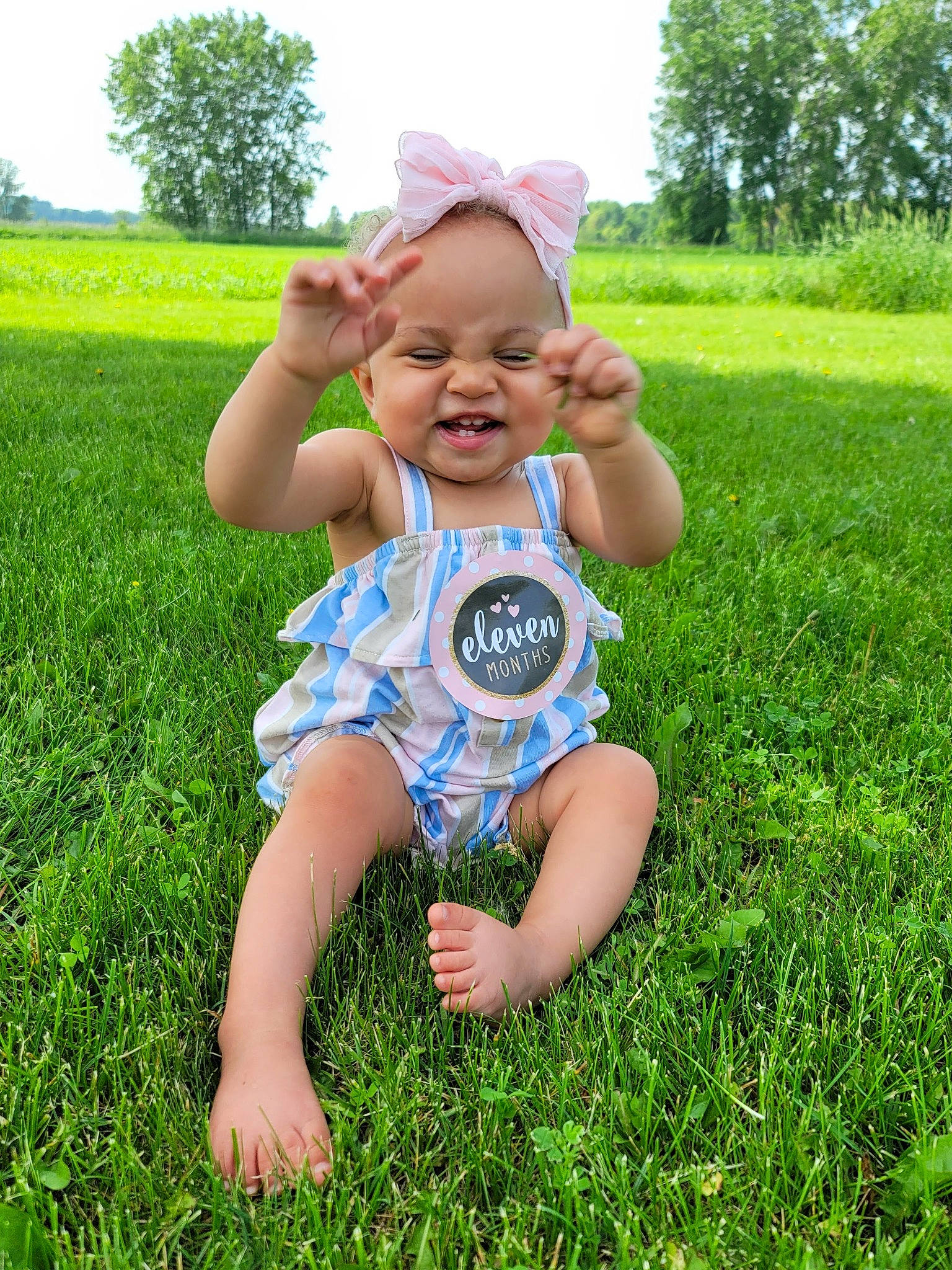 Emilah is registered to the contest to win money with this photo: baby_toddler_clothing, child, fun, grass, grassland, green, groundcover, happy, hat, headwear, lawn, leaf, meadow, natural_environment, people_in_nature, person, plant, sky, smile, sunlight