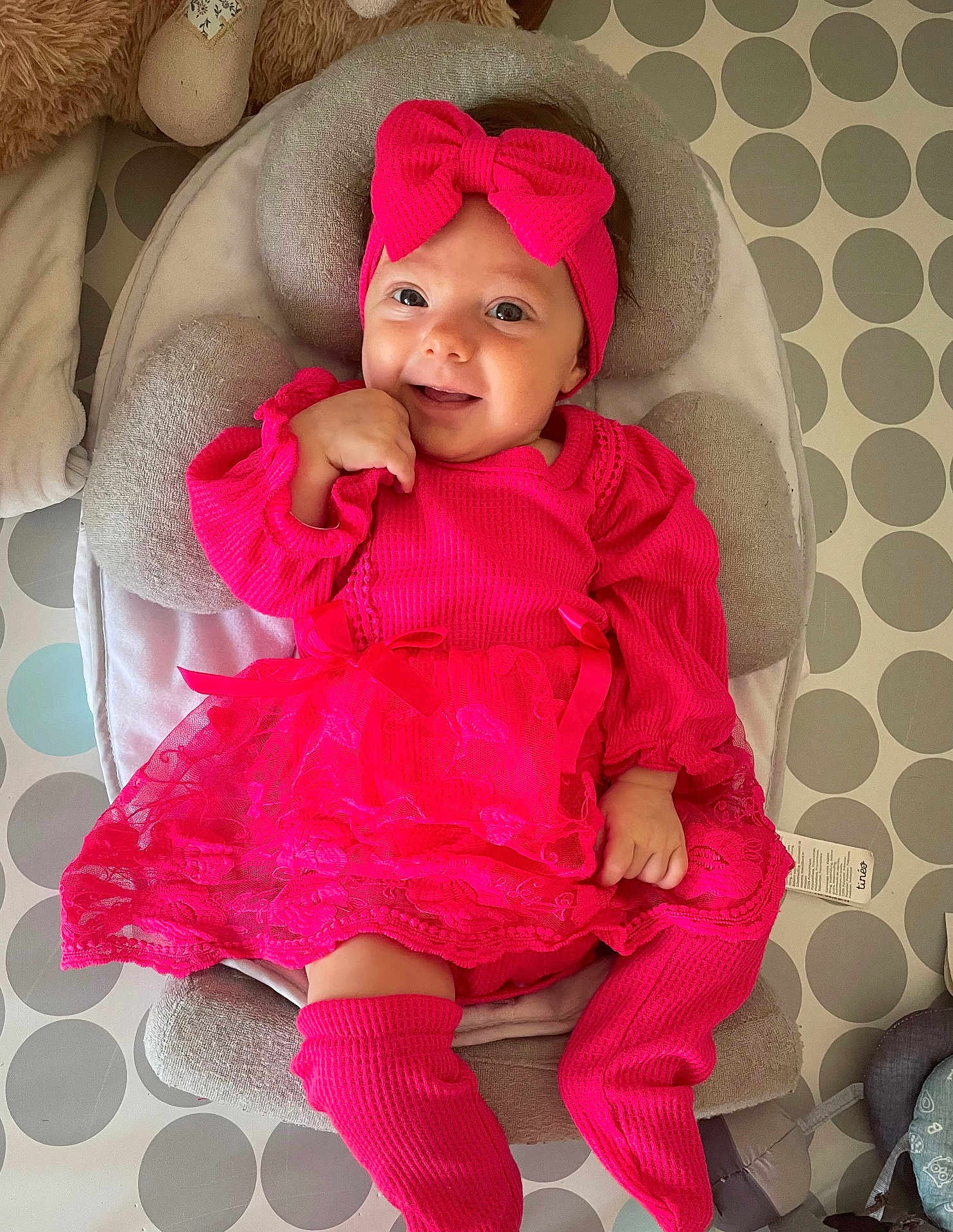 Bonnie participe au concours pour gagner de l'argent avec cette photo : baby, infant, pink_clothing, bow, headband, smiling, happy, cushion, baby_seat, patterned_floor, polka_dots, indoor, child, cute, portrait, sitting, woolen_clothing, toddler, playful, comfortable