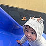 baby, child, slide, blue_slide, hoodie, outdoor, playground, curious, climbing, reindeer_hood, onesie, face, cute, infant, young_child, expression, hand, floor, toy, winter_clothing