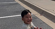 Eziah joined the competition — help win amazing prizes! child, toddler, smiling, outdoor, parking_lot, sidewalk, casual_clothing, crocs, happy, clapping, shorts, tshirt, trees, buildings, sunny, daytime, pavement, grass, suburban, person