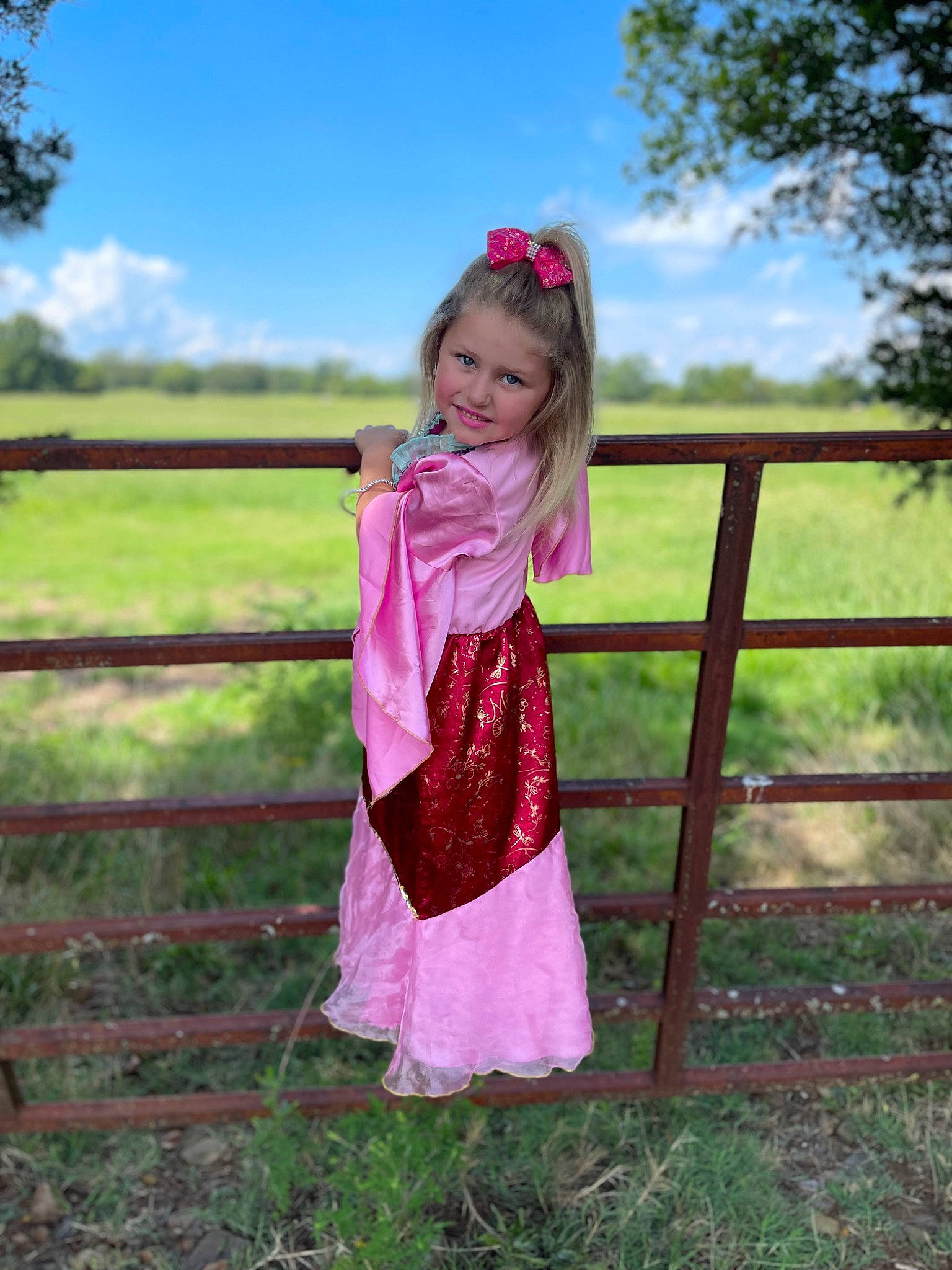 Kimber is registered to the contest to win money with this photo: baby_toddler_clothing, cloud, day_dress, fence, fun, grass, grassland, happy, leisure, magenta, meadow, one_piece_garment, people_in_nature, person, plant, prairie, sky, sleeve, smile, toddler