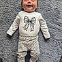 Lacey joined the competition — help win amazing prizes! baby, infant, smiling, happy, cute, clothing, onesie, pants, patterned_clothing, bow, hair_bow, lying_down, rug, soft_texture, indoor, child, person, footwear, white_socks, portrait