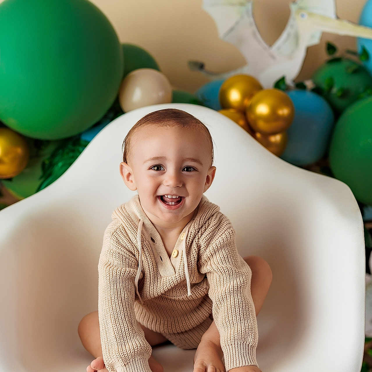 Steele joined the competition — help win amazing prizes! baby, balloons, celebration, chair, child, colorful, cute, decor, feet, hands, happy, indoor, knit_sweater, modern_furniture, playful, portrait, pterodactyl, seated, smiling, toddler