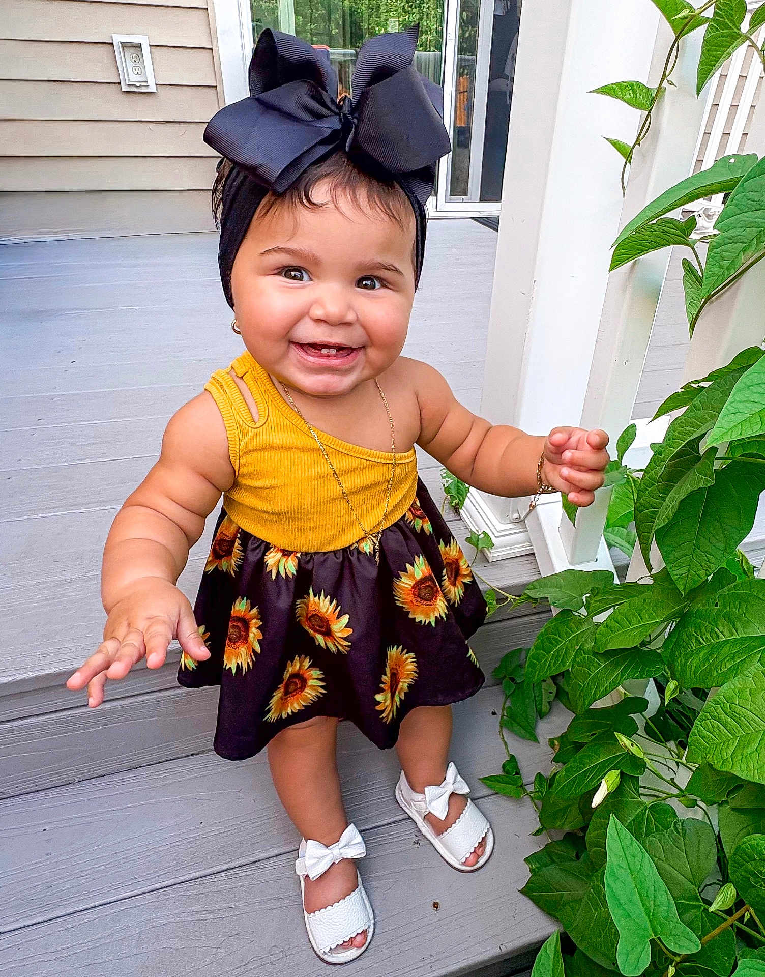 Galileia joined the competition — help win amazing prizes! toddler, child, smiling, yellow_top, sunflower_dress, headband, bow, outdoor, porch, plants, greenery, white_sandals, happy, cute, baby, feet, jewelry, bracelet, necklace, summer