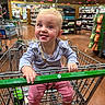 Kataleya is registered to the contest to win money with this photo: baby, child, shopping_cart, grocery_store, blue_eyes, pink_pants, long_sleeve_shirt, smiling, tongue_out, indoor, person, shopping, retail, aisle, handrail, metal_cart, floor, woman, blonde_hair, cute