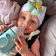 Kataleya is registered to the contest to win money with this photo: baby, infant, child, face, blue_eyes, headband, flower, bottle, sippy_cup, blanket, seat, straps, hand, clothing, portrait, cute, indoors, soft_light, skin, expression