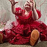 Kára is registered to the contest to win money with this photo: baby, background, bubbles, carpet, celebration, child, cute, fabric, footwear, hands_up, happy, indoor, person, playful, portrait, red_dress, sitting, smile, sparkle, texture