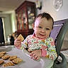 Kára joined the competition — help win amazing prizes! child, cookie, cute, eating, face, food, hair, hand, happy, high_chair, home, indoor, pajamas, person, seat, smile, snack, table, toddler, young_child