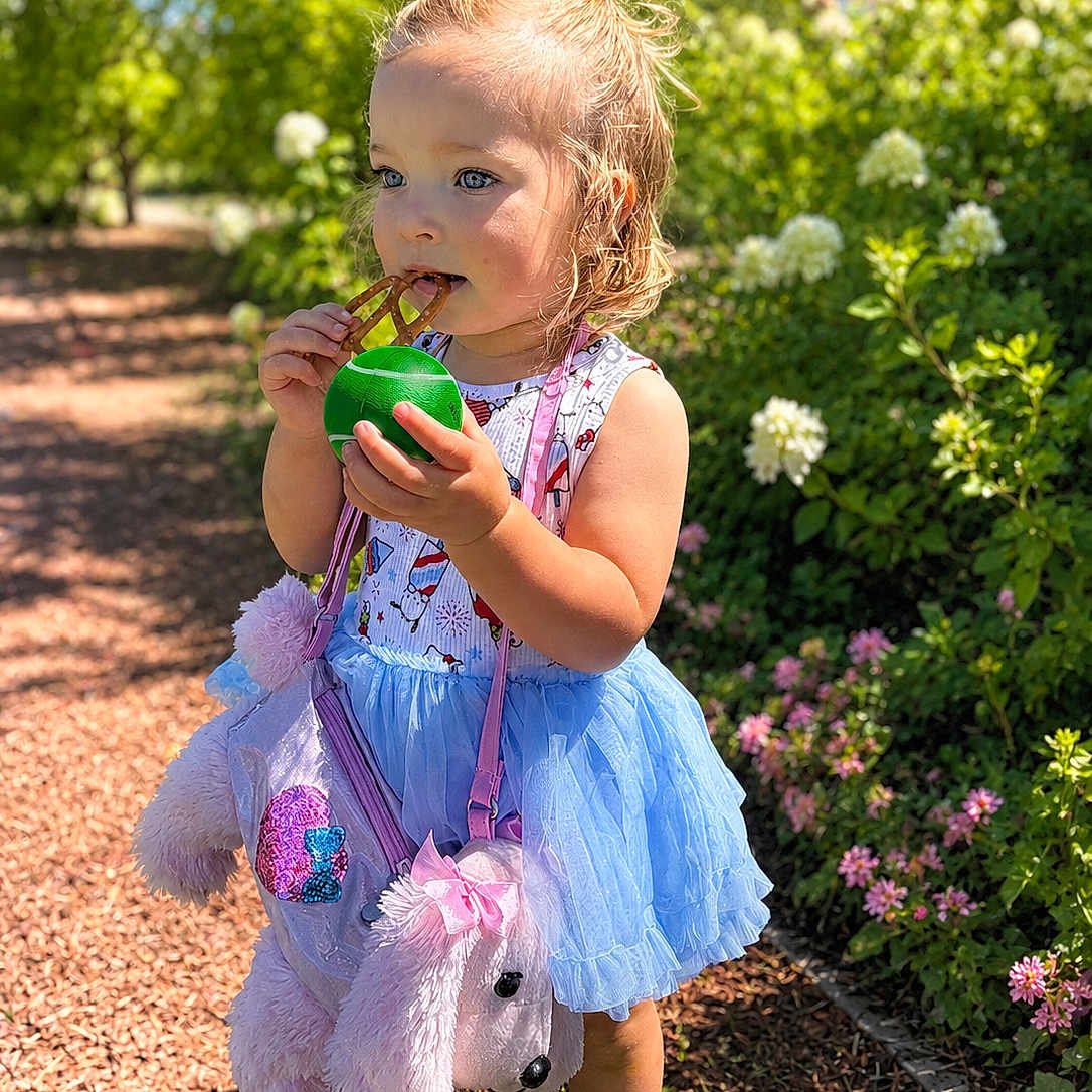 Halstyn joined the competition — help win amazing prizes! toddler, child, outdoor, sunny, greenery, flowers, pretzel, ball, blue_tutu, pink_purse, stuffed_animal, hair_tied, cute, walking_path, nature, daylight, shoes, playful, garden, portrait
