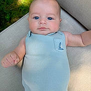 Brooks is registered to the contest to win money with this photo: baby, infant, face, blue_eyes, onesie, sleeveless_clothing, cushion, beige, outdoor, grass, sunlight, cute, child, portrait, skin, person, small_hand, relaxing, summer, closeup
