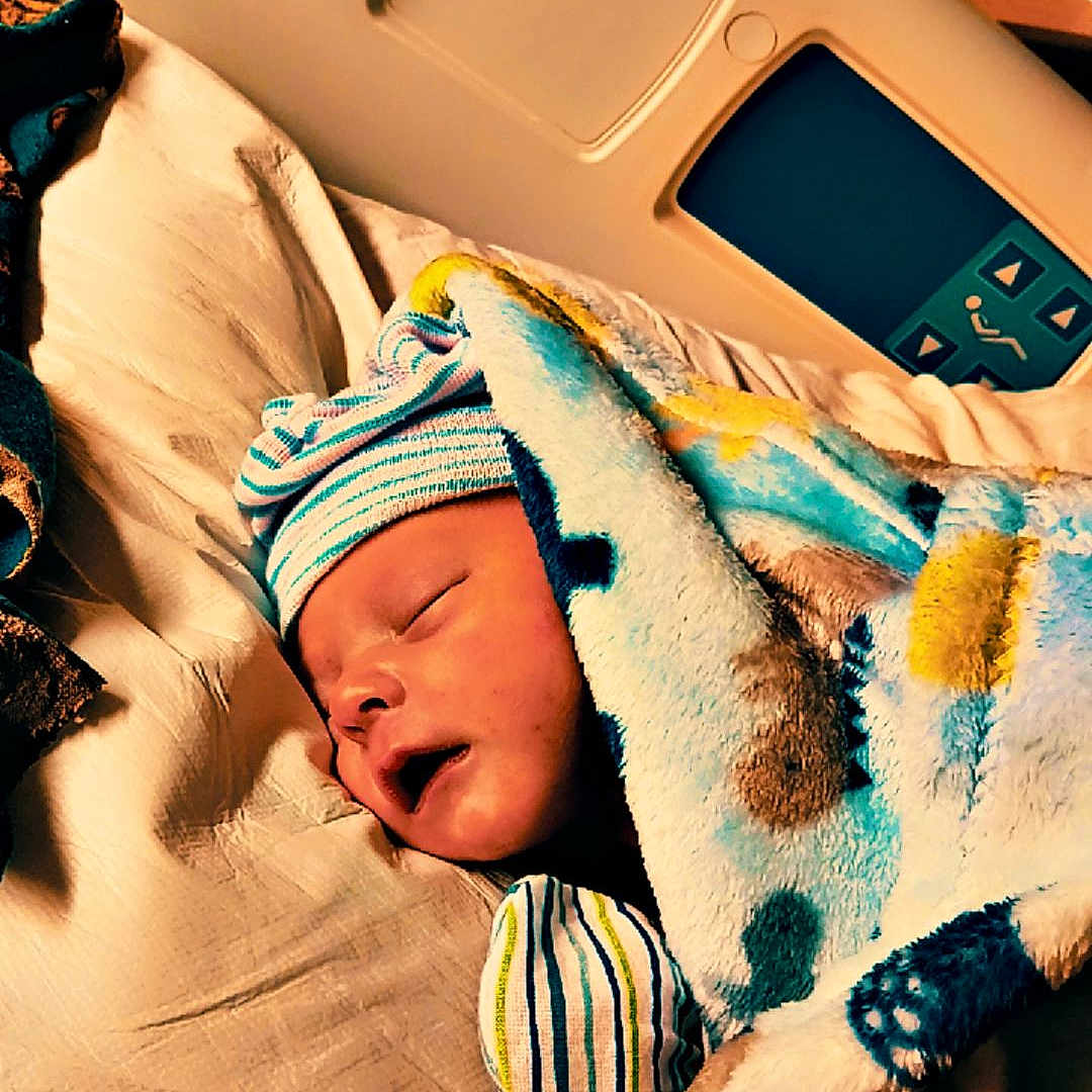 Secil is registered to the contest to win money with this photo: baby, bed, blanket, child, comfort, cute, face, hat, healthcare, hospital_bed, indoors, infant, newborn, peaceful, person, resting, sleeping, soft, striped, wrapped
