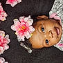 baby, flower, headband, pink_flower, infant, child, portrait, cute, smile, face, eyes, clothing, pattern, floral, lying_down, black_background, soft_texture, adorable, young_child, closeup