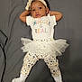 Azari is registered to the contest to win money with this photo: baby, bow, casual, child, colorful_text, cute, fashion, gray_background, headband, hearts, infant, lying_down, patterned_pants, portrait, relaxed, smiling, tutu_skirt, white_shirt, white_socks, young