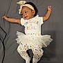 arms_outstretched, baby, bow, child, clothing, cute, grey_background, happy, headband, indoor, infant, leggings, lying_down, person, playful, portrait, smiling, toddler, tulle_skirt, white_socks