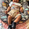 baby, smiling, curly_hair, sitting, tshirt, shorts, sneakers, cushion, animal_print, lion, elephant, zebra, whale, cloud, indoor, happy, child, person, cute, playful