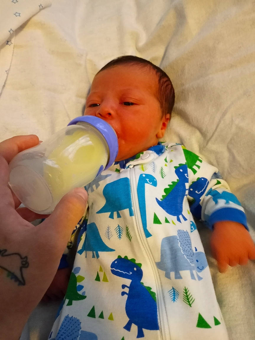 Josiah is registered to the contest to win money with this photo: baby, baby_bottle, baby_products, baby_sleeping, baby_toddler_clothing, bottle, child, comfort, drink, drinking, drinkware, infant_formula, milk, nail, person, plant_milk, plastic_bottle, skin, sleeve, toddler