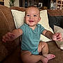 baby, child, smiling, happy, couch, living_room, onesie, arm, foot, pillow, furniture, indoor, person, face, blue_eyes, skin, home, cute, seated, infant