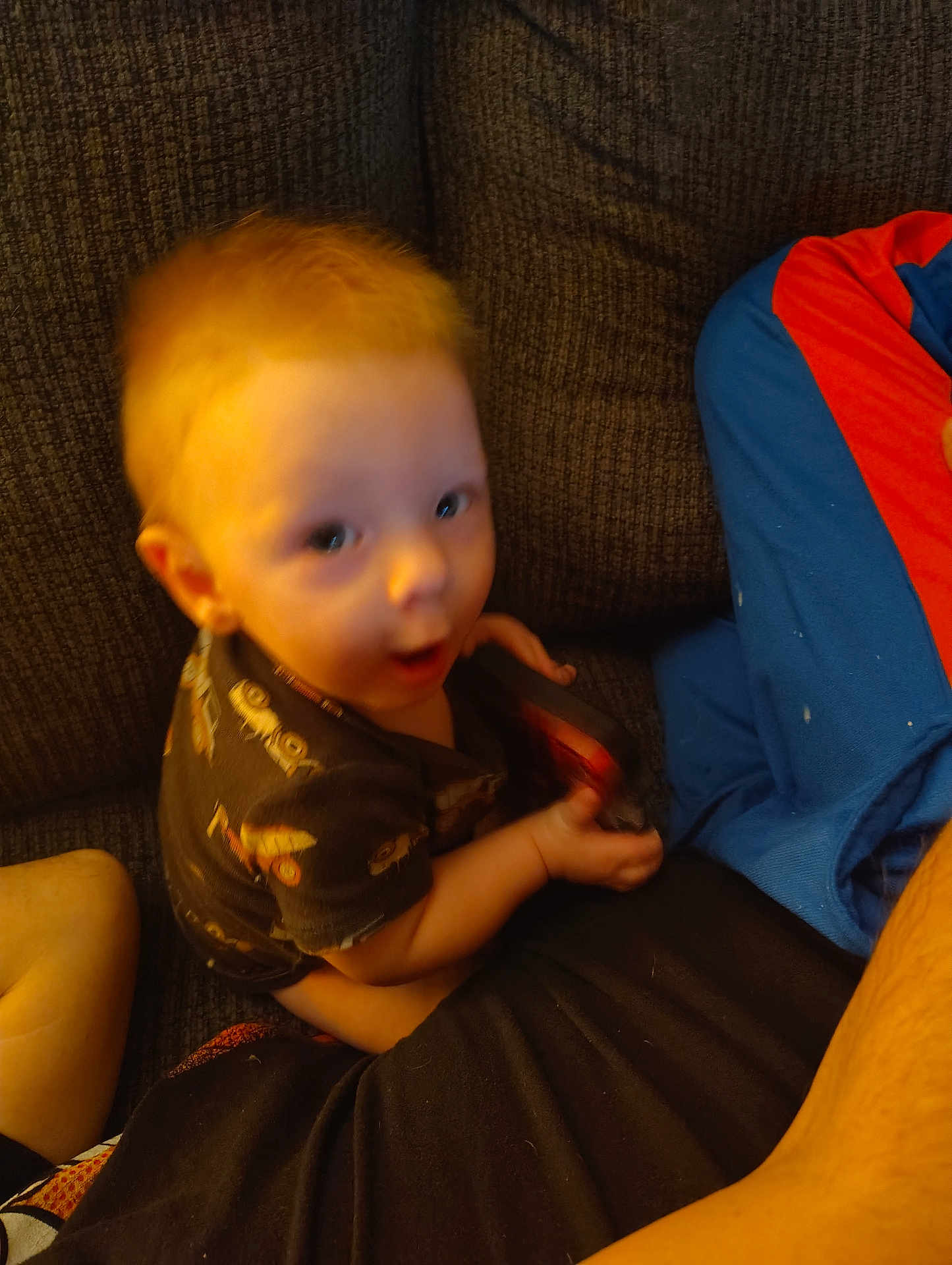 Caleb is registered to the contest to win money with this photo: toddler, child, red_hair, couch, indoor, curious, blurry, shirt, patterned_clothing, cushion, blanket, person, seated, home, expression, small_child, furniture, soft_lighting, casual, cozy