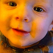 Caleb is registered to the contest to win money with this photo: baby, close_up, face, eyes, smile, child, infant, clothing, button, cute, portrait, young, warm_light, skin, nose, mouth, apparel, expression, happy, indoors