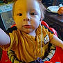Caleb is registered to the contest to win money with this photo: toddler, child, baby_walker, yellow_shirt, indoor, face, food, messy, curious, person, red_baby_walker, toy, furniture, room, head, expression, closeup, seat, young_child, home