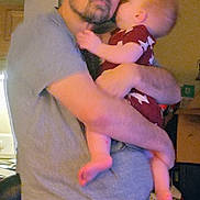 Caleb is registered to the contest to win money with this photo: affection, baby, beard, blurred, cabinet, casual, child, clothing, facial_hair, furniture, glasses, holding, home, indoor, love, man, parent, person, short_sleeves, toddler