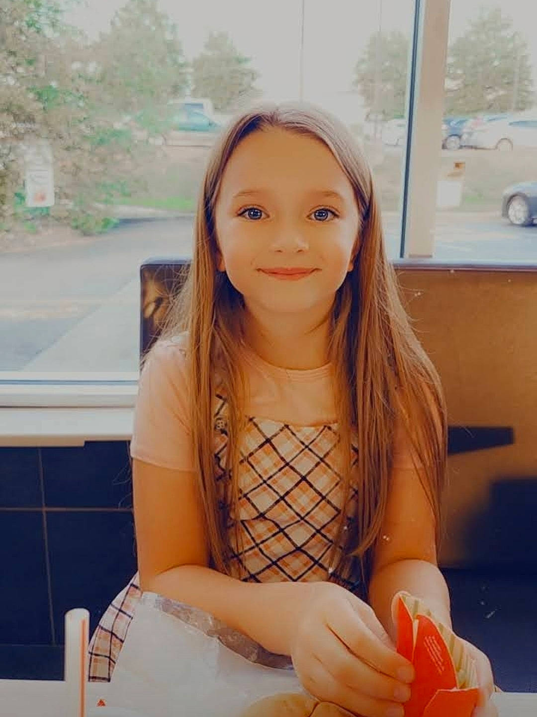 Isabella is registered to the contest to win money with this photo: abdomen, arm, blond, brown_hair, chair, child, hand, happy, human_leg, jewellery, joy, knee, necklace, person, sitting, skin, smile, t_shirt, table, tableware