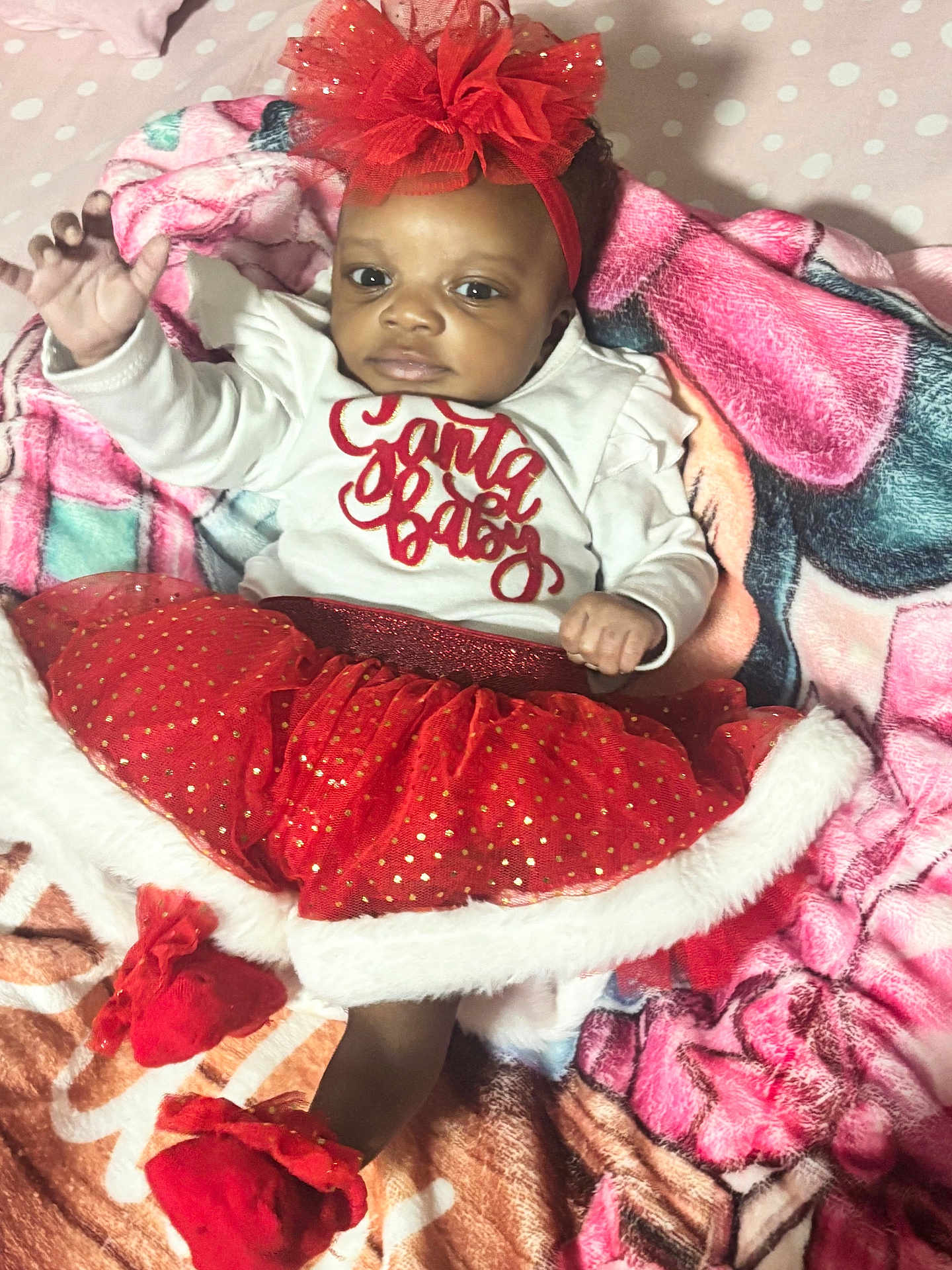 Dalylah is registered to the contest to win money with this photo: baby, infant, child, red_tutu, headband, blanket, polka_dots, holiday_outfit, cute, smiling, indoors, portrait, clothing, festive, soft_toys, bed, cozy, happy, person, christmas