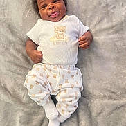 Amir joined the competition — help win amazing prizes! baby, infant, smiling, tongue_out, pajamas, bear_pattern, white_clothing, lying_down, blanket, soft_texture, cute, child, person, indoors, happy, portrait, young, face, skin, hands