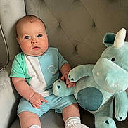Franco Robert is registered to the contest to win money with this photo: baby, child, plush_toy, unicorn, stuffed_animal, armchair, clothing, socks, person, indoor, cute, soft_toy, seated, furniture, infant, portrait, young_child, cushion, fabric, comfort