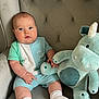 baby, child, plush_toy, unicorn, stuffed_animal, armchair, clothing, socks, person, indoor, cute, soft_toy, seated, furniture, infant, portrait, young_child, cushion, fabric, comfort