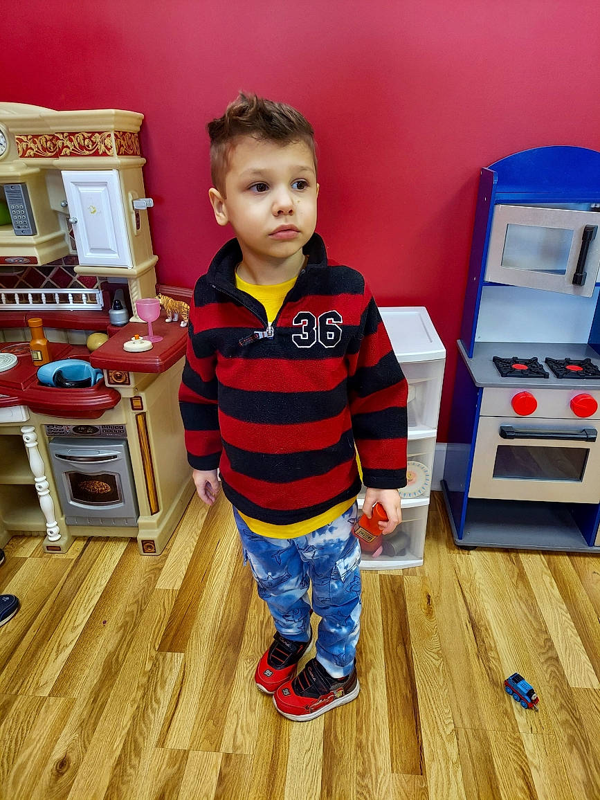 Sebastian is registered to the contest to win money with this photo: baby_toddler_clothing, child, floor, flooring, fun, gadget, hardwood, laminate_flooring, machine, orange, outerwear, person, room, sleeve, standing, t_shirt, toddler, varnish, wood, wood_flooring