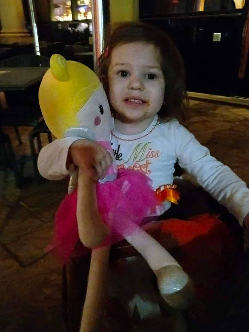 Calista is registered to the contest to win money with this photo: baby, baby_toddler_clothing, cheek, child, event, flooring, fun, happy, party, party_supply, person, play, room, sitting, smile, stuffed_toy, t_shirt, television, thumb, toddler