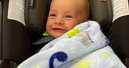 Emmett is registered to the contest to win money with this photo: baby, blanket, car_seat, child, cozy, eyes, fabric, face, happy, head, indoors, infant, portrait, safety_labels, sitting, smiling, text, travel, vehicle, wrapped
