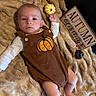 Emmett joined the competition — help win amazing prizes! autumn, baby, blanket, brown_outfit, child, costume, cozy, fall, fluffy_blanket, indoor, infant, lying_down, onesie, photography, portrait, pumpkin, seasonal, sign, toy, wide_eyed