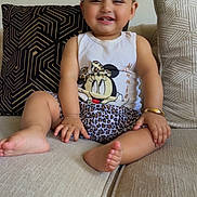 Khadijah joined the competition — help win amazing prizes! toddler, child, smiling, sitting, couch, indoor, face, happy, clothing, tank_top, shorts, patterned_cushion, hair_ties, barefoot, skin, person, cute, playful, leopard_print, minnie_mouse