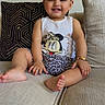 toddler, child, smiling, sitting, couch, indoor, face, happy, clothing, tank_top, shorts, patterned_cushion, hair_ties, barefoot, skin, person, cute, playful, leopard_print, minnie_mouse