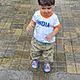 boy, casual, casual_wear, child, clothing, curious, daylight, footwear, looking_down, outdoor, pavement, person, sandals, short_hair, standing, street, tiles, toddler, wet_pavement, young_child