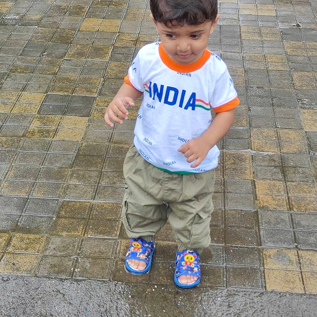 Umar Akhlaque Malik is registered to the contest to win money with this photo: boy, casual, casual_wear, child, clothing, curious, daylight, footwear, looking_down, outdoor, pavement, person, sandals, short_hair, standing, street, tiles, toddler, wet_pavement, young_child