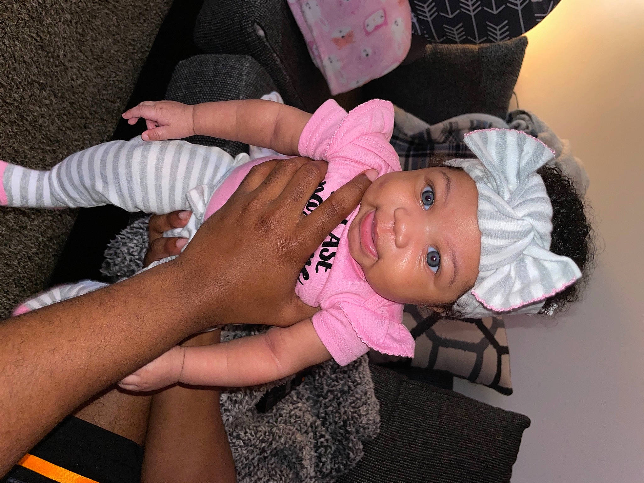 Averi is registered to the contest to win money with this photo: arm, baby, baby_toddler_clothing, cheek, child, comfort, eye, face, finger, foot, happy, hat, head, headwear, nail, person, pink, skin, smile, textile