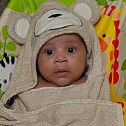 Jaden is registered to the contest to win money with this photo: baby, child, towel, hood, bear, animal_print, cushion, colorful, face, eyes, cute, infant, wrapped, curious, expression, indoors, soft, texture, portrait, young