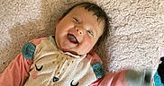 Aurora joined the competition — help win amazing prizes! baby, smiling, lying_down, blanket, onesie, happy, infant, child, cute, soft_texture, waving_hand, indoors, face, clothing, head, person, joyful, playful, cozy, expression