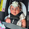 baby, car_seat, headband, flower, child, infant, seatbelt, blanket, clothing, cute, indoors, portrait, sitting, straps, safety, happy, face, person, closeup, infancy