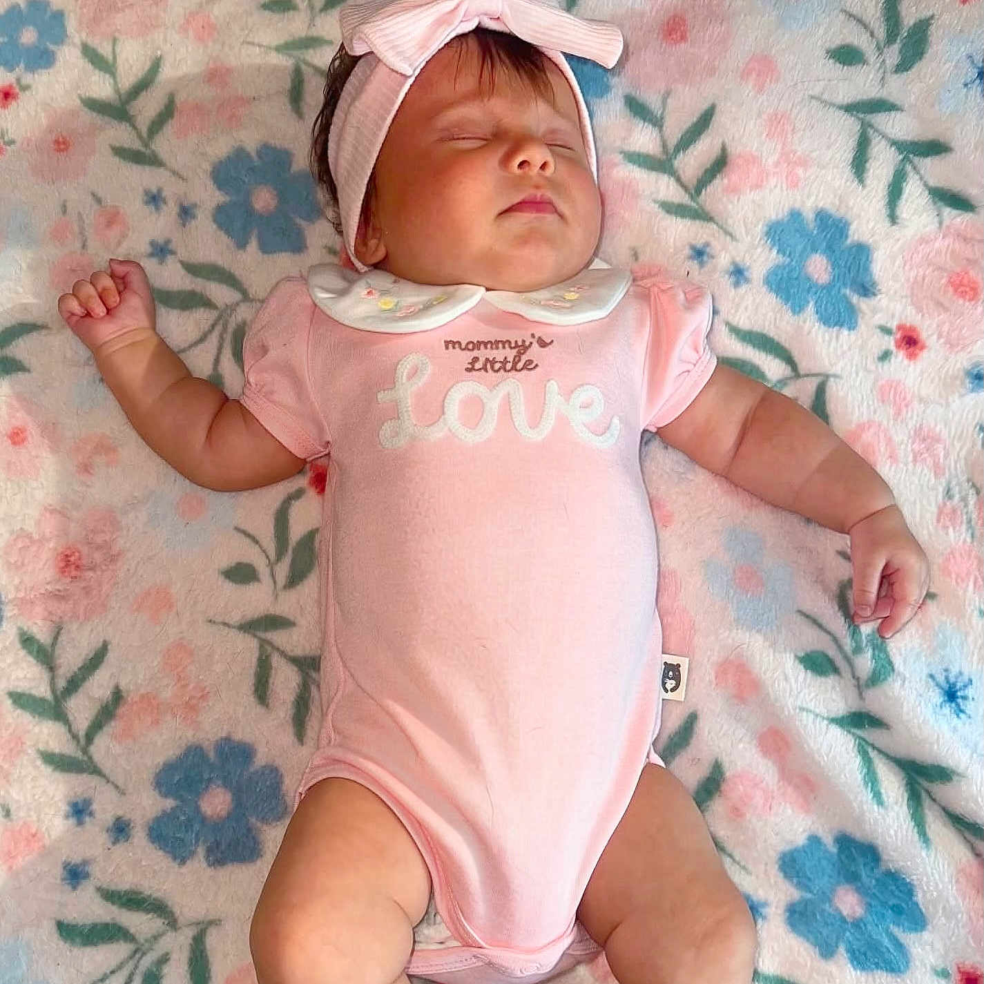 Aurora is registered to the contest to win money with this photo: baby, sleeping, pink_onesie, headband, blanket, floral_pattern, infant, peaceful, cute, child, soft, adorable, lying_down, small, closed_eyes, toddler, indoors, candid, portrait, relaxed