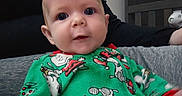 Aria is registered to the contest to win money with this photo: baby, blanket, clothing, couch, dress, face, furniture, happy, head, knitwear, pajamas, person, photography, portrait, quilt, shirt, sitting, smile, sweater, t_shirt