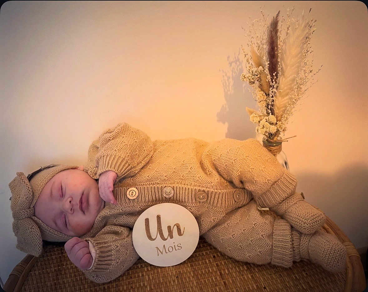 Giulia participe au concours pour gagner de l'argent avec cette photo : baby, infant, sleeping_baby, knitted_outfit, bow_headband, milestone_sign, wicker_basket, dried_flowers, pampas_grass, neutral_background, cozy, portrait, newborn_photography, beige, soft_texture, peaceful, buttons, hand, socks, laying_down