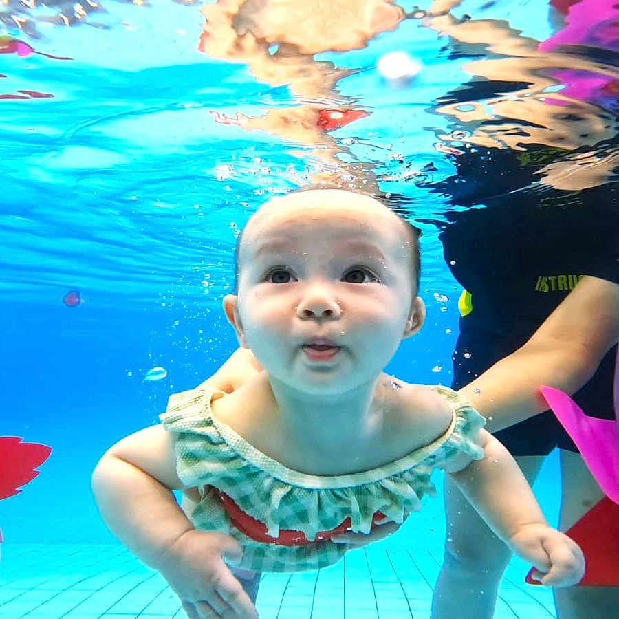 Elliora Amaria Foose is registered to the contest to win money with this photo: baby, underwater, swimming_pool, child, person, water, colorful, floating, toy, playful, support, bright, blue, frilly_swimsuit, cute, face, cheeks, expression, adult, fun