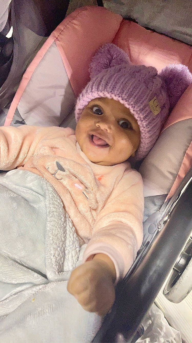 Kimora is registered to the contest to win money with this photo: auto_part, baby, baby_carriage, baby_products, cap, car_seat, cheek, child, comfort, eye, face, family_car, fun, happy, head, headwear, mouth, outerwear, person, smile